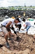28日,在素瓦那普国际机场附近,志愿者用沙袋筑起防洪堤坝。新华社发